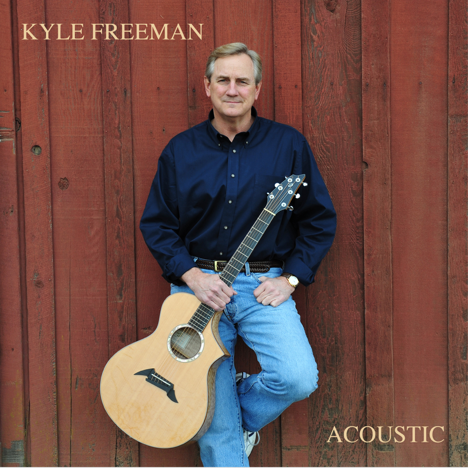Album cover for Acoustic by Kyle Freeman featuring Kyle standing with an acoustic guitar against a red wooden wall